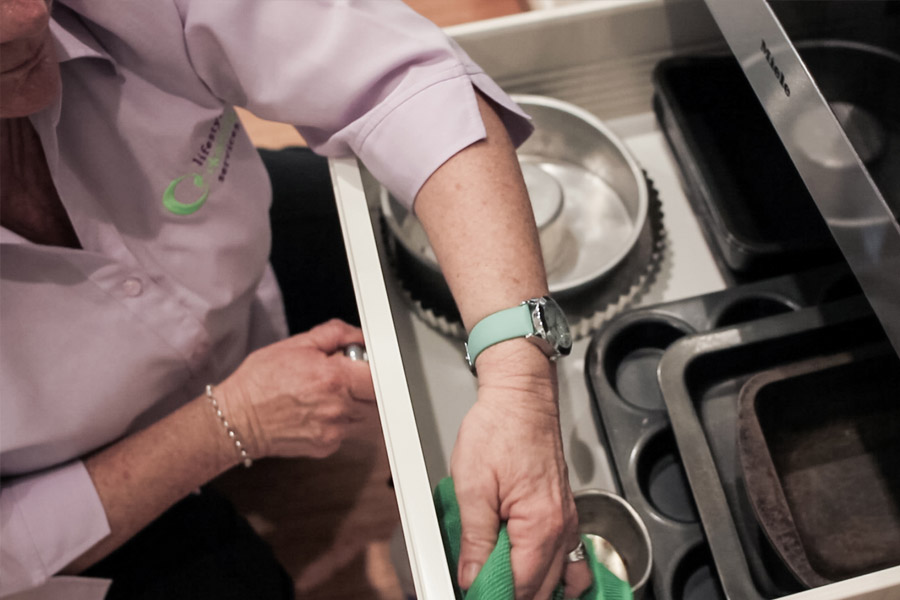 lifestylecleaningwomanwipingdrawersfilledwithbakingtools